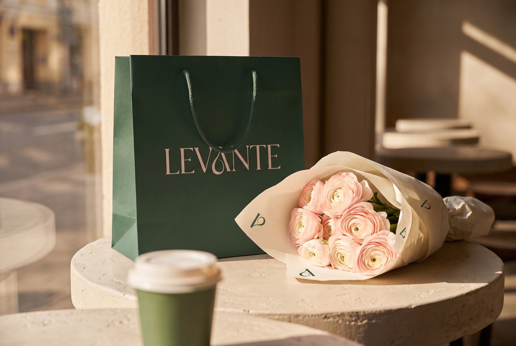Levante carrier bag, wrapped bouquet and coffee cup on a cafe table