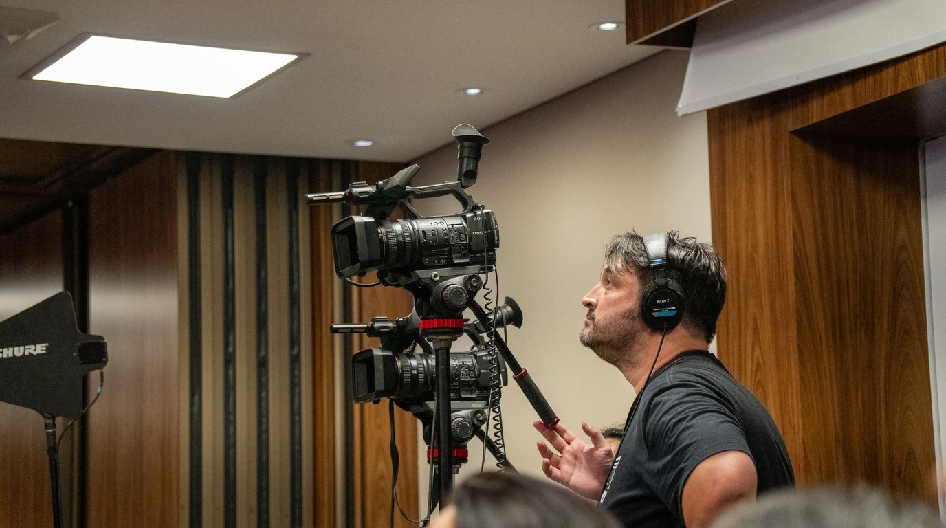 Stock photo: a camera operator with headphones filming an indoor event on professional cameras