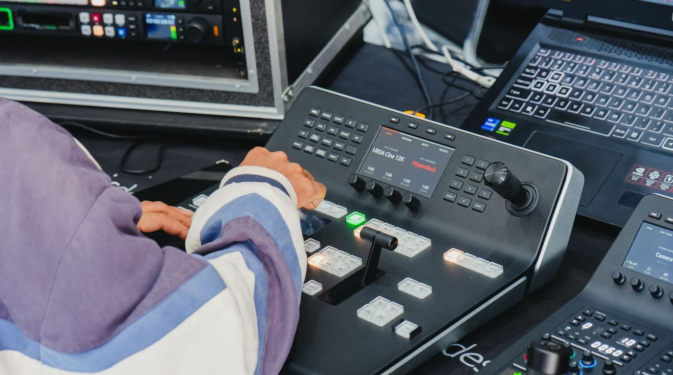 Stock photo: an operator at a compact video switcher panel, with rack equipment beside it