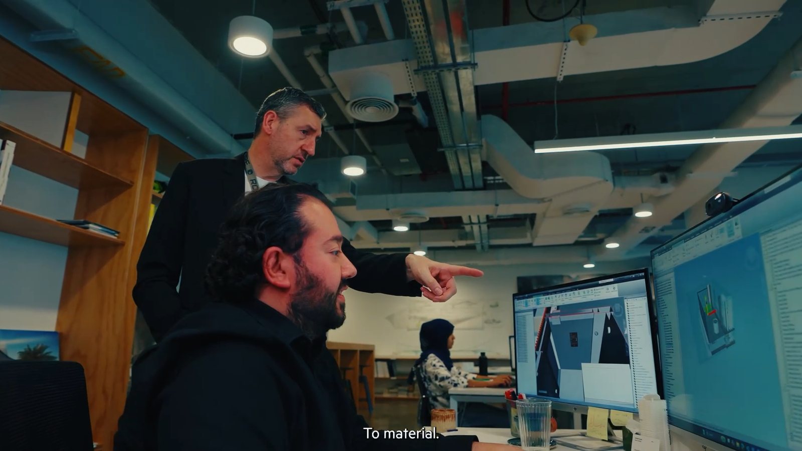 Two colleagues reviewing a project on large monitors at a desk, a frame from our LWK + Partners film