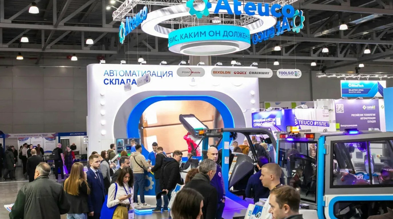 A busy exhibition hall with visitors at a lit exhibition stand