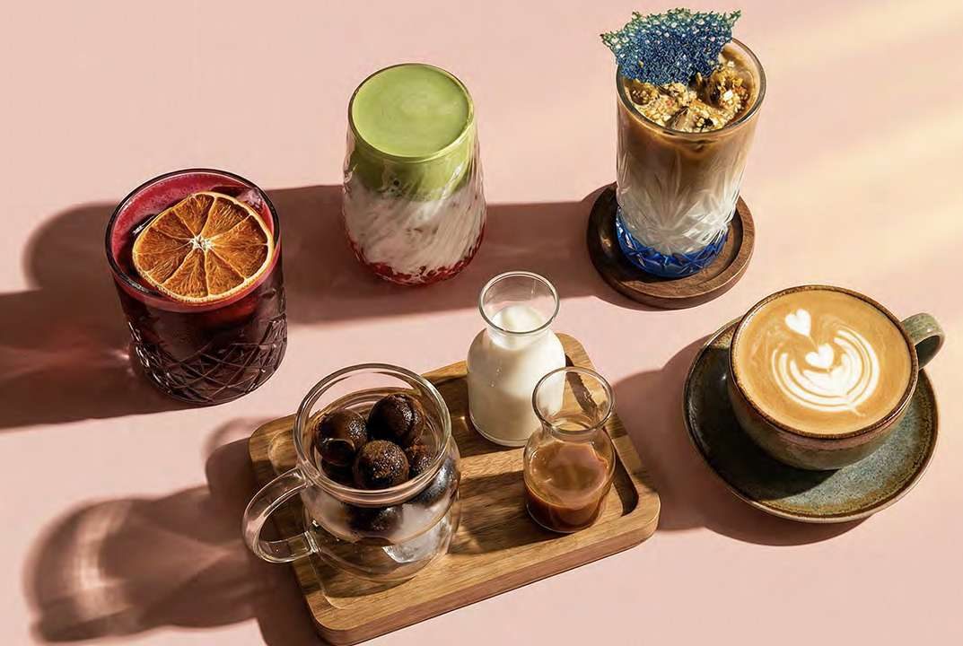 A flat lay of coffees and cold drinks on a wooden tray