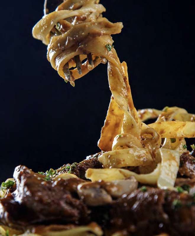 Pasta lifted on a fork over braised beef